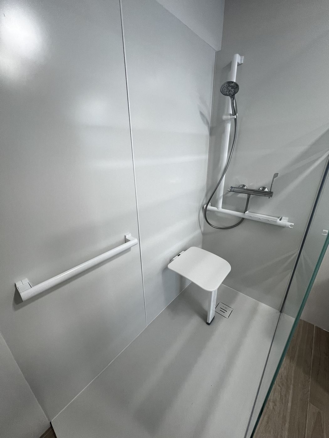 Salle de bain rénovée par Nouvel Espace — douche à l'italienne avec barre d'appui et siège